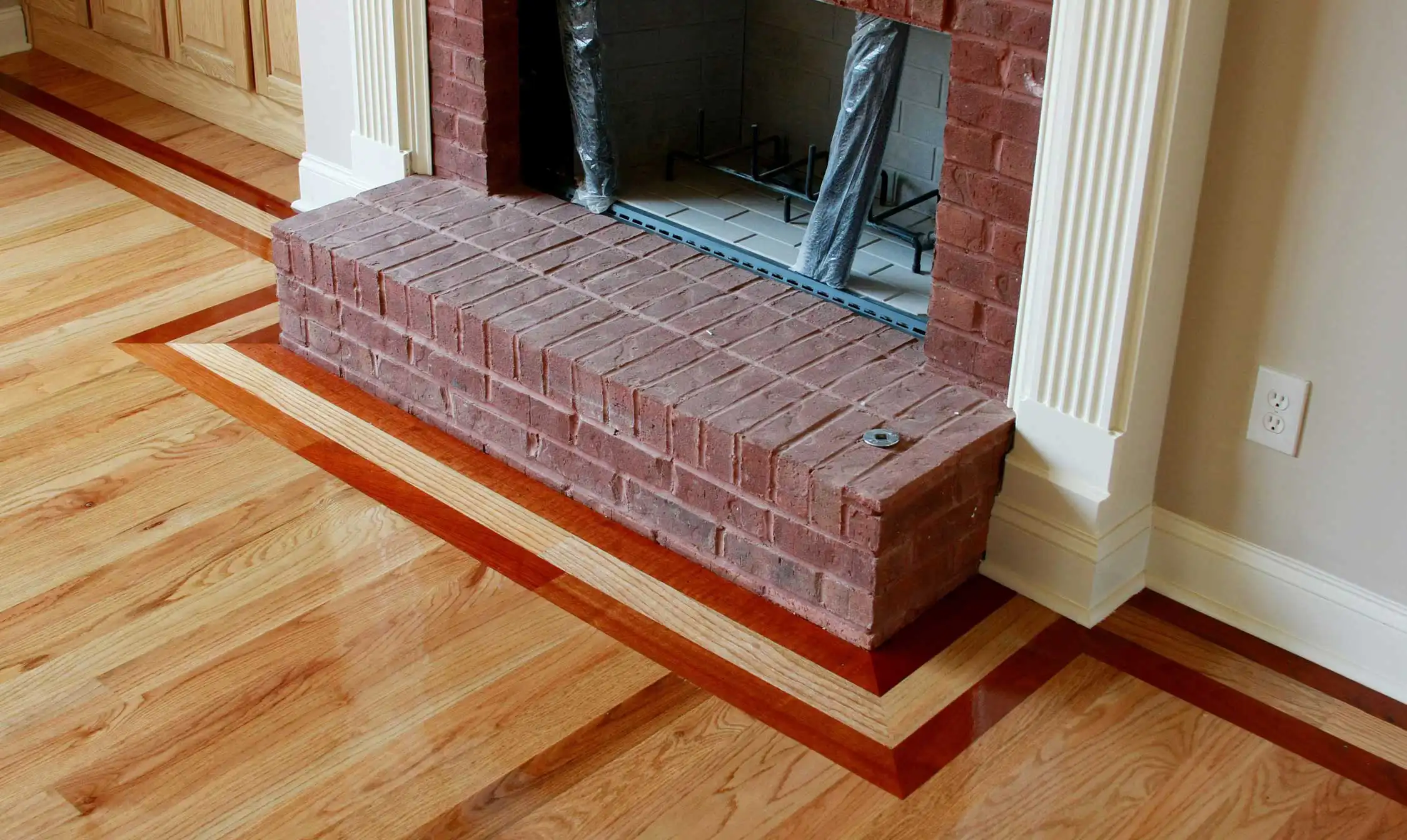 A contrasting hardwood border framing a brick fireplace hearth